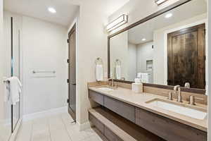 Full bathroom featuring light tile patterned flooring, double vanity, recessed lighting, and a stall shower