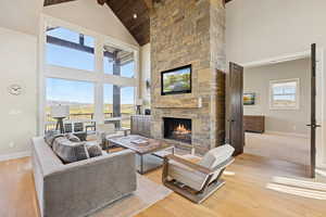 Living room with high vaulted ceiling, light wood finished floors, a fireplace, and beamed ceiling