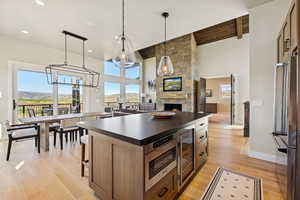 Kitchen featuring dark countertops, a fireplace, a kitchen island, hanging light fixtures, and appliances with stainless steel finishes
