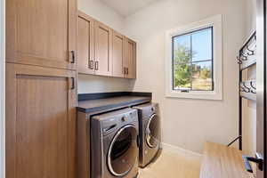Laundry area with light tile patterned floors, cabinet space, and separate washer and dryer