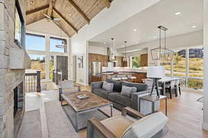Living area featuring a chandelier, a fireplace, high vaulted ceiling, a wooden ceiling with exposed beams, and recessed lighting