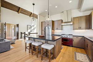 Kitchen featuring brown cabinetry, a kitchen island, premium appliances, a breakfast bar area, and decorative backsplash