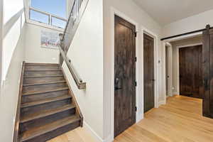 Stairway featuring wood finished floors and a barn door