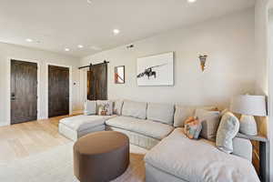 Living room featuring a barn door, recessed lighting, and light wood finished floors