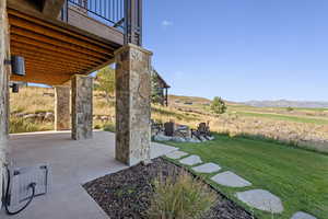 View of grassy yard with a patio, a mountain view, an outdoor fire pit, and a balcony