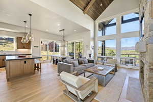Living area with light wood finished floors, a mountain view, plenty of natural light, high vaulted ceiling, and a wooden ceiling with exposed beams