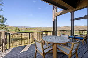 Wooden terrace featuring outdoor dining space, a mountain view, and view of golf course