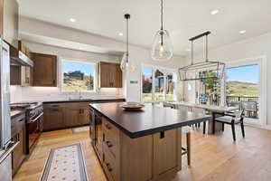 Kitchen with dark countertops, light wood-style flooring, pendant lighting, a center island, and recessed lighting