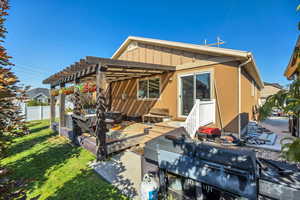 Rear view of property with a patio, a pergola, board and batten siding, and stucco siding