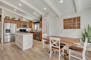 Kitchen with appliances with stainless steel finishes, brown cabinets, light wood-style flooring, a center island, and recessed lighting