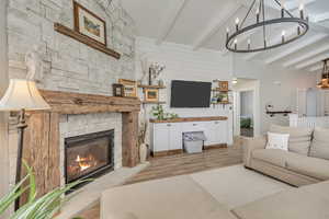 Living area featuring beamed ceiling, wood finished floors, a chandelier, and a fireplace