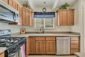 Kitchen with stainless steel appliances, beam ceiling, and brown cabinets