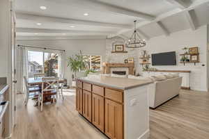 Kitchen featuring a chandelier, open floor plan, light countertops, a fireplace, and light wood finished floors