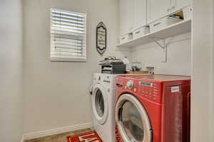Laundry room with washer and clothes dryer and light tile patterned floors
