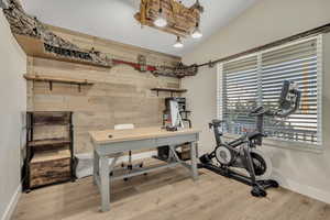 Office space featuring wooden walls, light wood-style flooring, and vaulted ceiling