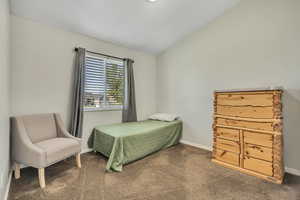 Carpeted bedroom with lofted ceiling and baseboards