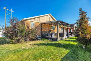 View of side of home with a wooden deck, a lawn, and a pergola