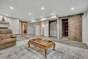 Living area with a barn door, recessed lighting, and wood finished floors