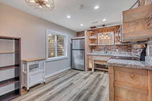 Kitchen featuring open shelves, stainless steel appliances, light wood-style flooring, recessed lighting, and light stone counters