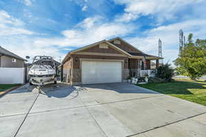 View of front of house featuring stone siding, concrete driveway, covered porch, and board and batten siding