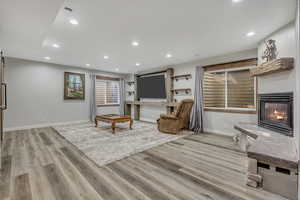 Living area featuring a glass covered fireplace, recessed lighting, light wood finished floors, and a barn door