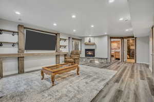Living room with recessed lighting, light wood-type flooring, and a glass covered fireplace