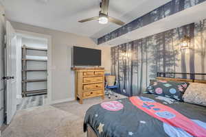 Carpeted bedroom with a ceiling fan and baseboards