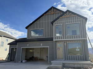 View of front of property featuring board and batten siding, a garage, and concrete driveway