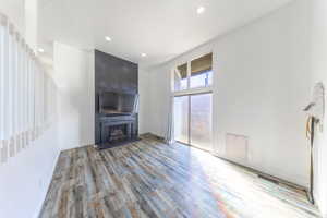 Unfurnished living room with recessed lighting, light wood-style flooring, a large fireplace, large windows, and a high ceiling. (Fireplace is currently  not working)