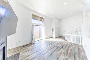 Unfurnished living room featuring a high ceiling, light wood-type flooring, recessed lighting, and a fireplace