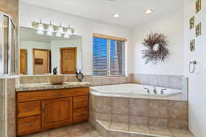 Master bathroom featuring separate tub and shower with dual sinks.