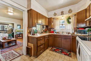 Kitchen featuring light countertops, white appliances, and brown cabinets