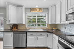 Kitchen with white cabinets, appliances with stainless steel finishes, decorative backsplash, and recessed lighting