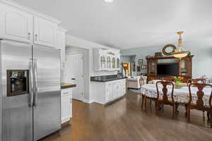 Kitchen with stainless steel fridge with ice dispenser, white cabinetry, dark wood-style flooring, and open floor plan