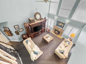 Living area with a high ceiling, a premium fireplace, and ceiling fan
