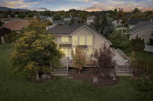 Traditional home featuring a deck, a front lawn, stucco siding, and stairway