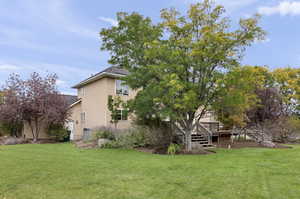 View of grassy yard with stairway and a deck