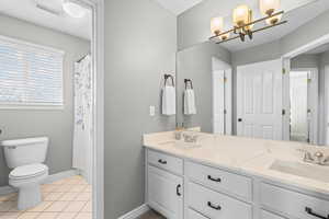 Full bathroom with double vanity, light tile patterned floors, a chandelier, and a shower with shower curtain