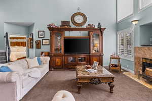 Carpeted living room with a fireplace and a towering ceiling
