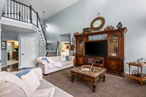 Living room featuring a high ceiling, stairway, and carpet