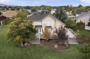 Back of property with a lawn, a deck, a residential view, stucco siding, and stairway
