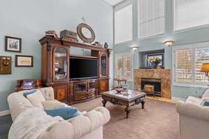 Carpeted living room featuring a towering ceiling, plenty of natural light, and a fireplace