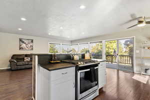 Kitchen with gas range, LVP Flooring, open floor plan, white cabinets, and recessed lighting
