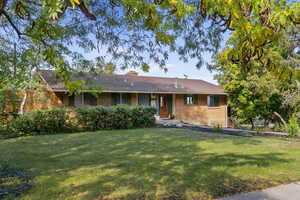 Single story home with brick siding, a front lawn, and a chimney