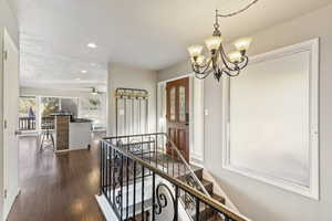 Hallway with an upstairs landing, recessed lighting, LVP Flooring, and a chandelier