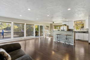 Living room with LVP Flooring, recessed lighting, textured ceiling, and ceiling fan