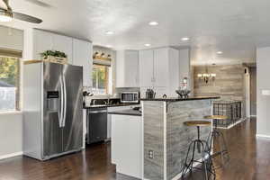 Kitchen with a breakfast bar, stainless steel appliances, LVP Flooring, and white cabinetry