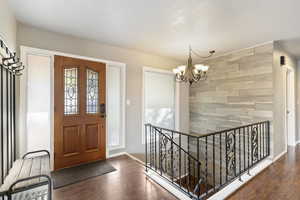 Foyer entrance featuring wood wall, LVP Flooring, and chandelier