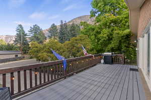 Wooden deck with a mountain view, area for grilling, and view of wooded area