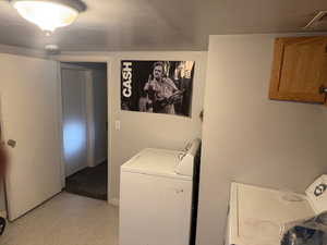 Washroom featuring washer and clothes dryer, cabinet space, and light floors